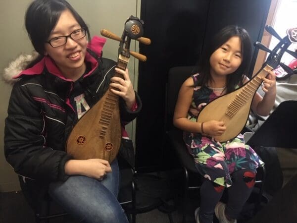 Two young girls holding instruments in a room.