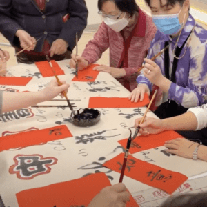 People writing Chinese calligraphy with brushes.