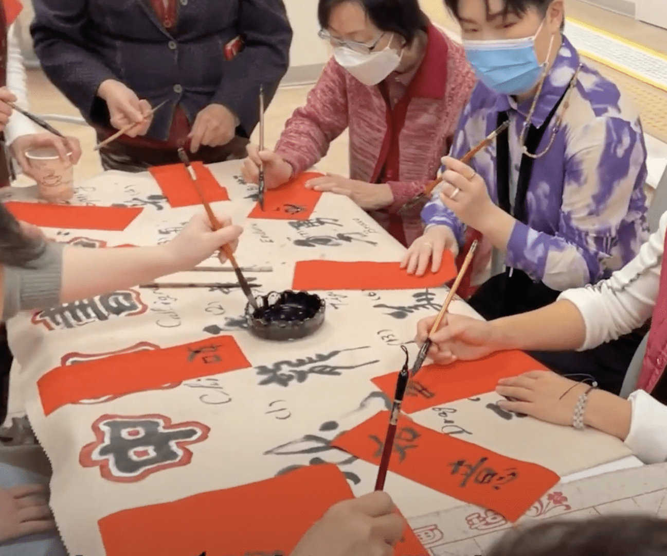 People writing Chinese calligraphy with brushes.