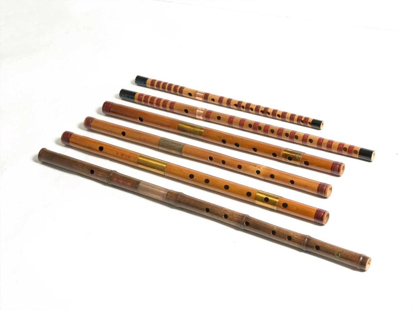 A collection of seven colorful wooden flutes (笛子) arranged diagonally on a white background.